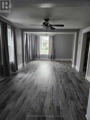 Niagara Falls (Clifton Hill) apartment for rent - A spacious room with a ceiling fan and wooden flooring.