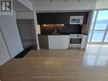 Toronto (Waterfront Communities) condo for rent - A kitchen with white cabinets and a black countertop.