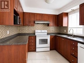 Markham (Middlefield) apartment for rent - A kitchen with wooden cabinets and a white stove top oven.