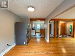 Brampton (Downtown Brampton) apartment for rent - A spacious room with wooden floors and a large refrigerator.