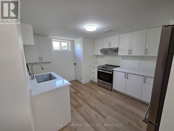 St. Catharines (Secord Woods) apartment for rent - A kitchen with white cabinets and a wooden floor.