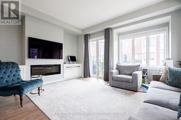 Oakville (Br Bronte) townhouse for rent - A living room with a blue velvet chair and grey couches.