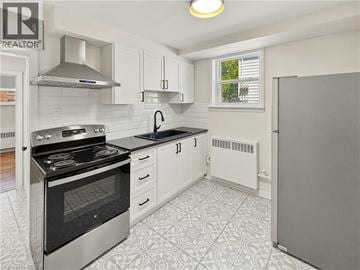 Brantford apartment for rent - A kitchen with a black stove top oven and white cabinets.