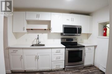 South Bruce Peninsula multi-family for rent - A kitchen with white cabinets and a black stove top oven.