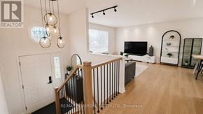 Petawawa apartment for rent - A well-lit living room with a television, a couch, and a staircase.