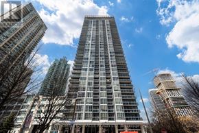 Mississauga (City Centre) condo for rent - A tall residential building stands in a city with a clear blue sky above.