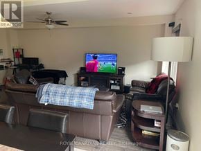 Hamilton (Stoney Creek Mountain) townhouse for rent - A living room with a brown couch and a television playing a game.