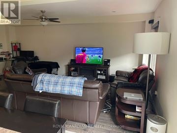 Hamilton (Stoney Creek Mountain) townhouse for rent - A living room with a brown couch and a television playing a game.