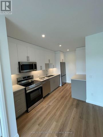 Kitchener condo for rent - A modern kitchen with wooden floors and stainless steel appliances.