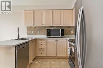 Burlington (Alton) townhouse for rent - A kitchen with wooden cabinets and a brick backsplash.
