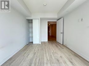 Toronto (Agincourt South-Malvern West) condo for rent - A spacious room with white walls and wooden flooring, featuring a white built-in shelf and a doorway leading to another room.