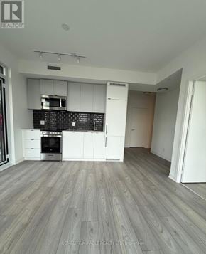 Toronto (South Parkdale) condo for rent - A modern kitchen with wooden flooring and white cabinetry.