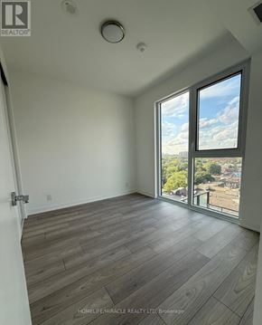 Toronto (South Parkdale) condo for rent - A room with a large window and wooden flooring.