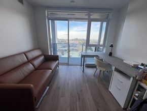 Surrey apartment for rent - A brown leather couch sits in a room with a desk and chair.
