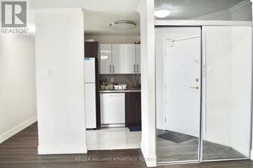 Mississauga (City Centre) condo for rent - A white door is open to a kitchen with white cabinets and a white fridge.