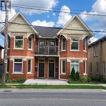 Guelph (Exhibition Park) fourplex for rent - A two-story brick house with a balcony on the second floor.