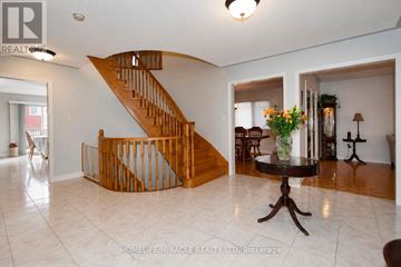 Mississauga (East Credit) apartment for rent - A living room with a wooden staircase and a round table with a vase of flowers on it.