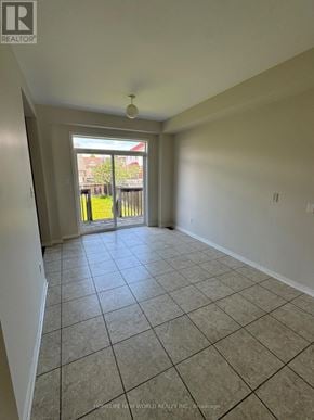 Oshawa (Pinecrest) apartment for rent - A spacious room with tiled flooring and a view of a backyard through a sliding glass door.