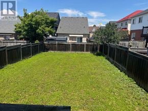 Oshawa (Pinecrest) apartment for rent - A backyard with a wooden fence and a green lawn.