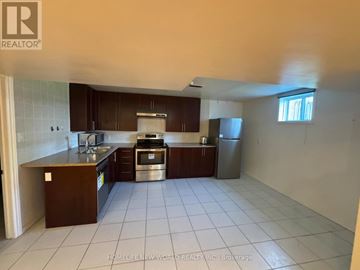 Oshawa (Pinecrest) apartment for rent - A kitchen with white tiled floors and brown cabinets.