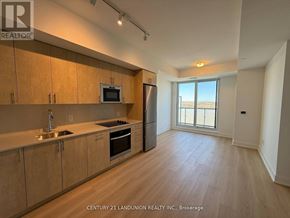 Oshawa (Windfields) condo for rent - A kitchen with wooden cabinets and a microwave above the oven.