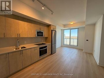 Oshawa (Windfields) condo for rent - A kitchen with wooden cabinets and a microwave above the oven.