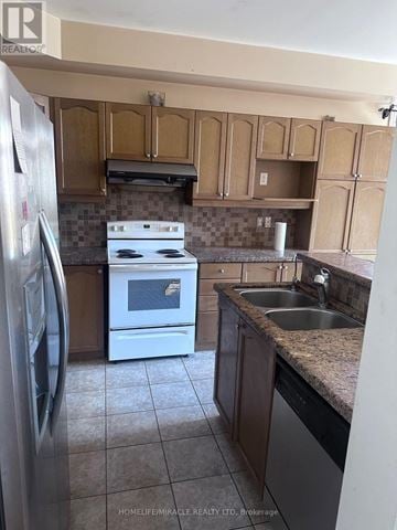 Brampton (Sandringham-Wellington) apartment for rent - A kitchen with a white stove and a refrigerator.