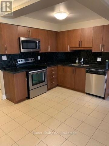 Guelph (Downtown) condo for rent - A kitchen with brown cabinets and black countertops.