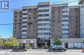Guelph (Downtown) condo for rent - A large building with a sign that says "Planet Realty Inc Brokerage" in front of it.