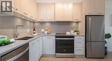 Vancouver apartment for rent - A modern kitchen with white cabinets and stainless steel appliances.