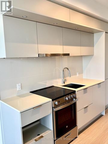 Mississauga (City Centre) condo for rent - A modern kitchen with white cabinets and a black stove top.