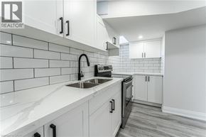 Stoney Creek apartment for rent - A modern kitchen with white cabinets and a marble countertop.
