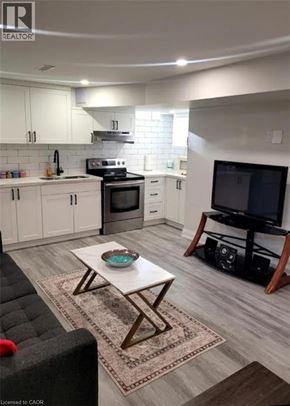 Stoney Creek apartment for rent - A modern kitchen with white cabinets and a black sofa.