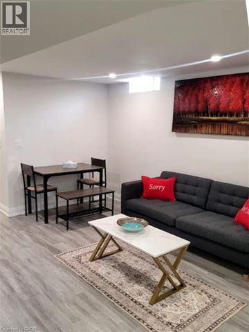 Stoney Creek apartment for rent - A living room with a grey couch, a white coffee table, and a painting on the wall.