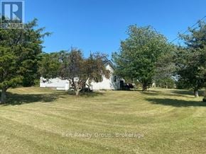 Prince Edward County (Hillier) apartment for rent - A white house is surrounded by trees in a grassy field.