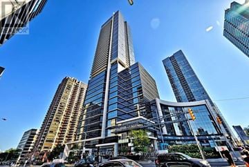 Toronto (Willowdale East) condo for rent - A tall building with a glass facade stands in the middle of a bustling city street.