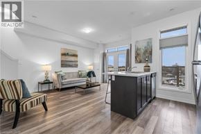Beamsville townhouse for rent - A well-lit, spacious living room with a striped armchair and a kitchen area with a refrigerator and sink.