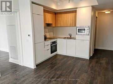 Toronto (Banbury-Don Mills) condo for rent - A kitchen with white cabinets and a microwave built into the counter.