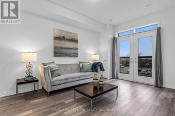 Lincoln (Beamsville) townhouse for rent - A living room with a grey couch, a painting on the wall, and a glass door leading to a balcony.