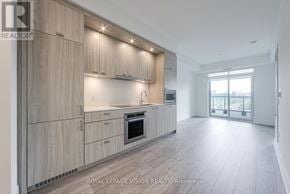 Toronto (Dovercourt-Wallace Emerson-Junction) condo for rent - A modern kitchen with wooden cabinets and a stainless steel oven.