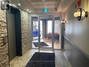 London North (North G) condo for rent - A hallway with a stone wall and a glass door leading to a balcony.