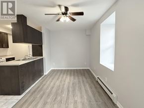 Guelph (Downtown) multi-family for rent - A room with a ceiling fan and a kitchen area with cabinets and a sink.
