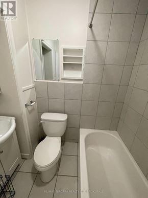 Welland (Lincoln/Crowland) apartment for rent - A white toilet sits in a bathroom next to a white sink and a white bathtub.