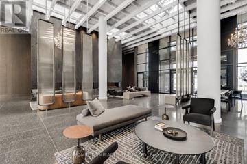 Vaughan (Vaughan Corporate Centre) condo for rent - A modern living room with a glass partition wall and a glass table with a bowl of fruit on it.