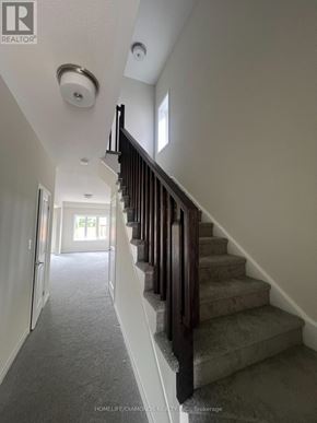 Brantford apartment for rent - A staircase with a wooden railing and a smoke detector on the ceiling.