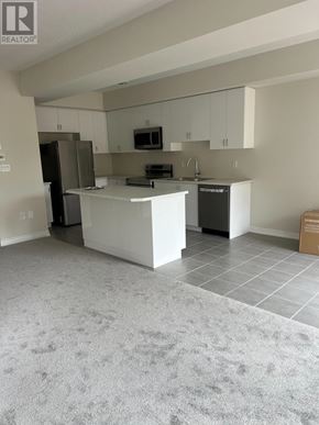 Brantford apartment for rent - A kitchen with a white island and a black refrigerator.