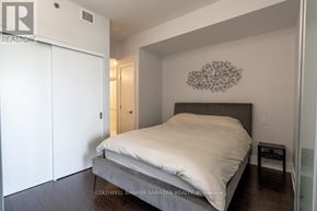 Ottawa condo for rent - A bedroom with a bed, a wall hanging, and a small table.