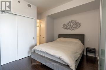 Ottawa condo for rent - A bedroom with a bed, a wall hanging, and a small table.