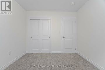 Brampton (Credit Valley) townhouse for rent - A white bedroom with two doors and a carpet floor.