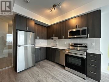 Pickering (Bay Ridges) condo for rent - A modern kitchen with dark wood cabinets and stainless steel appliances.